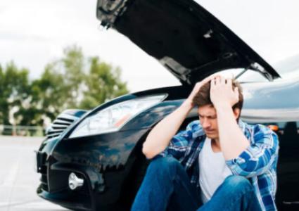Мужчина держится за голову, сидя у черного авто